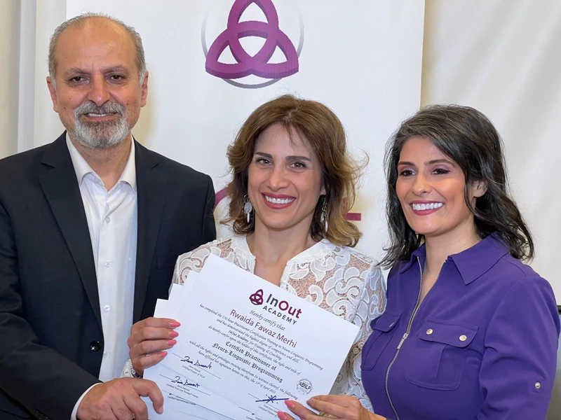 Rudy holding her certificate at her graduation, standing with her mentors.